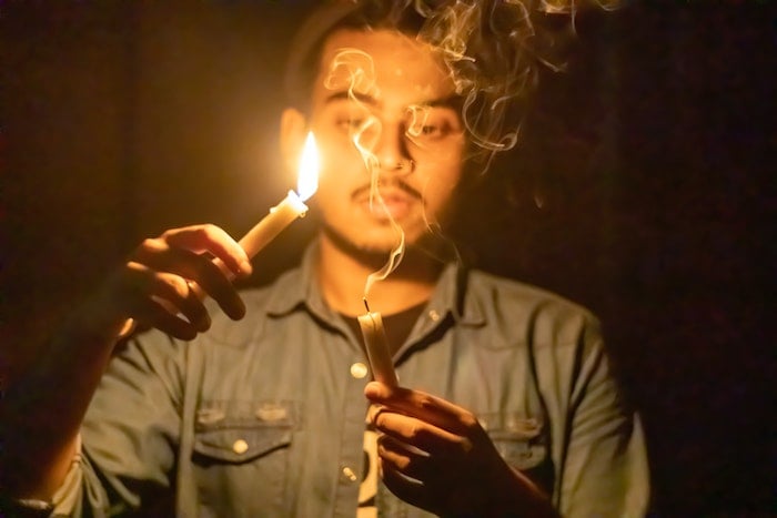 A person holding a lit candle above another smoking candle as an example for creative lighting ideas