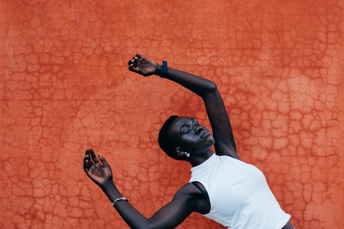 A conceptual editorial portrait of a woman falling back against an orange, textured background