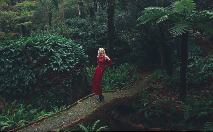 Woman in red dress standing on a forest bridge
