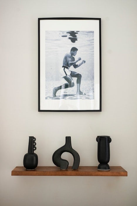 A framed photo of Mohammed Ali hangs above a wooden shelf