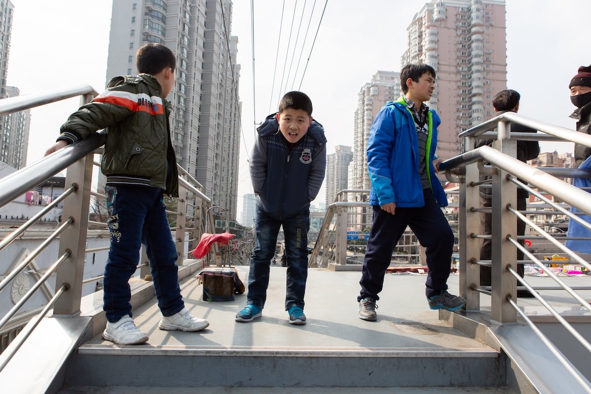 photograph of boys on a bridge in a city with a negative vignette