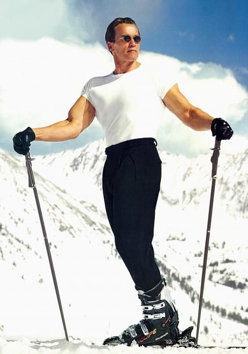 Arnold Schwarzenegger on skis with a white snowy mountain background 