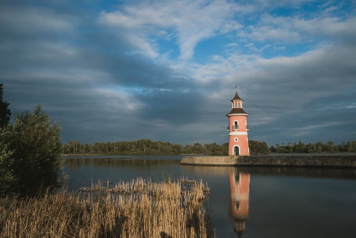 A pink tower next to a lake 
